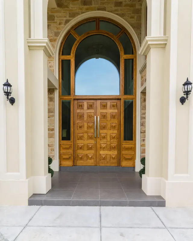 Natural timber double doors with a large arched glazed surround.
