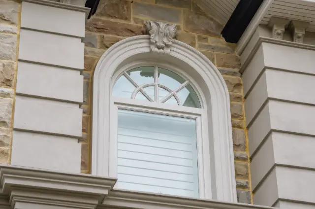 An arched timber window with matching exterior mouldings.