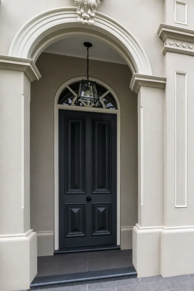 A dark timber entry door beneath a custom glazed fanlight.