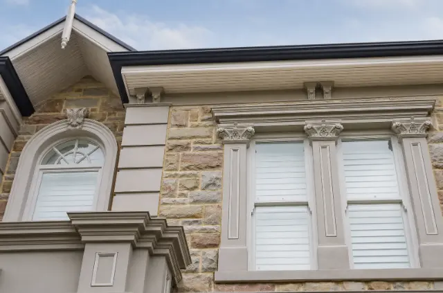 Custom timber windows with matching mouldings across a stone façade.